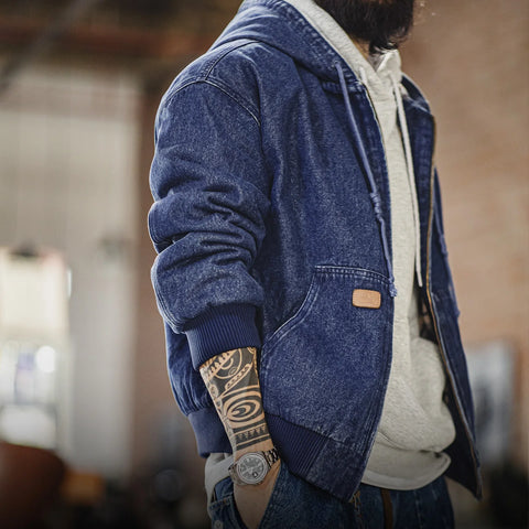 Person wearing a blue denim jacket with a blurred indoor background