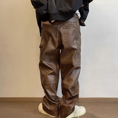 Person wearing brown leather pants against a plain background