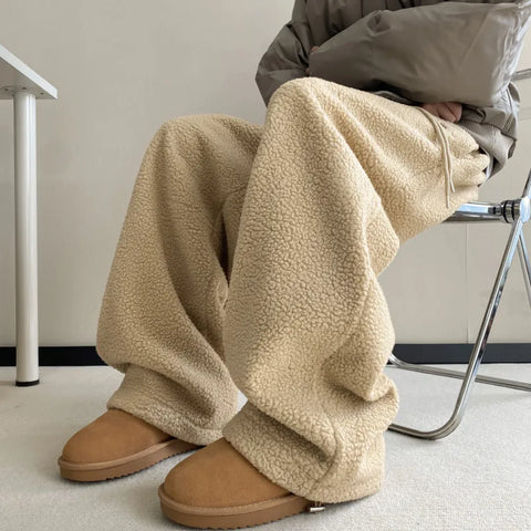 Person wearing beige fleece pants and brown shoes sitting on a chair.