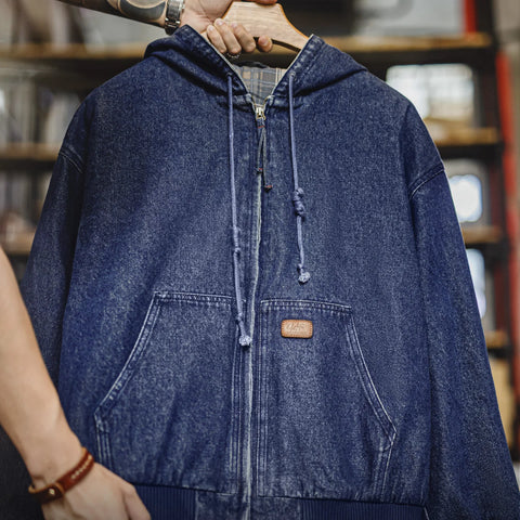 Blue denim jacket with a brand logo on a hanger against a blurred background