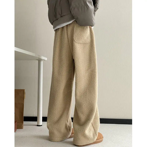 Person wearing beige wide-leg pants in a minimal indoor setting