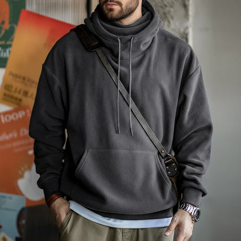 Person wearing a gray hoodie with a shoulder bag in an indoor setting