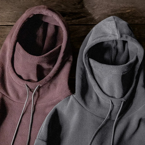 Two hoodies, one maroon and one gray, on a wooden surface.