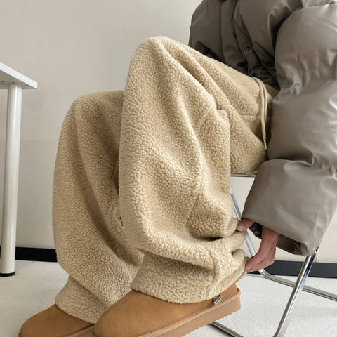 Person sitting on a chair with a beige fleece pants, wearing brown shoes.