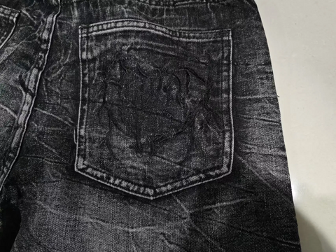 Close-up of a dark denim pocket on a jacket with a plain background